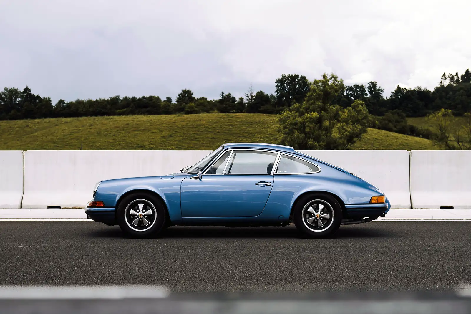 A vintage blue Porsche 911 parked on a road