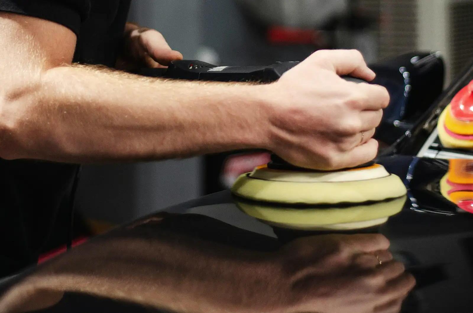 A detailer using a buffer to polish paint on a car