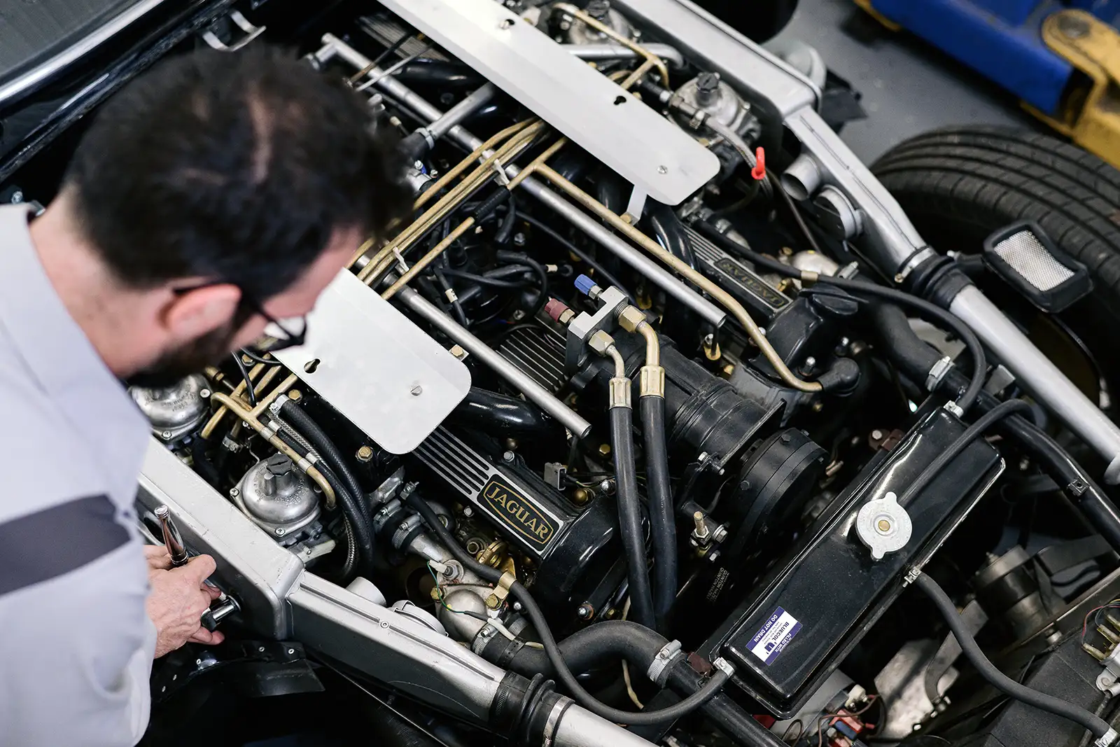 A mechanic working on a vintage Jaguar engine at Millrace Motor Club