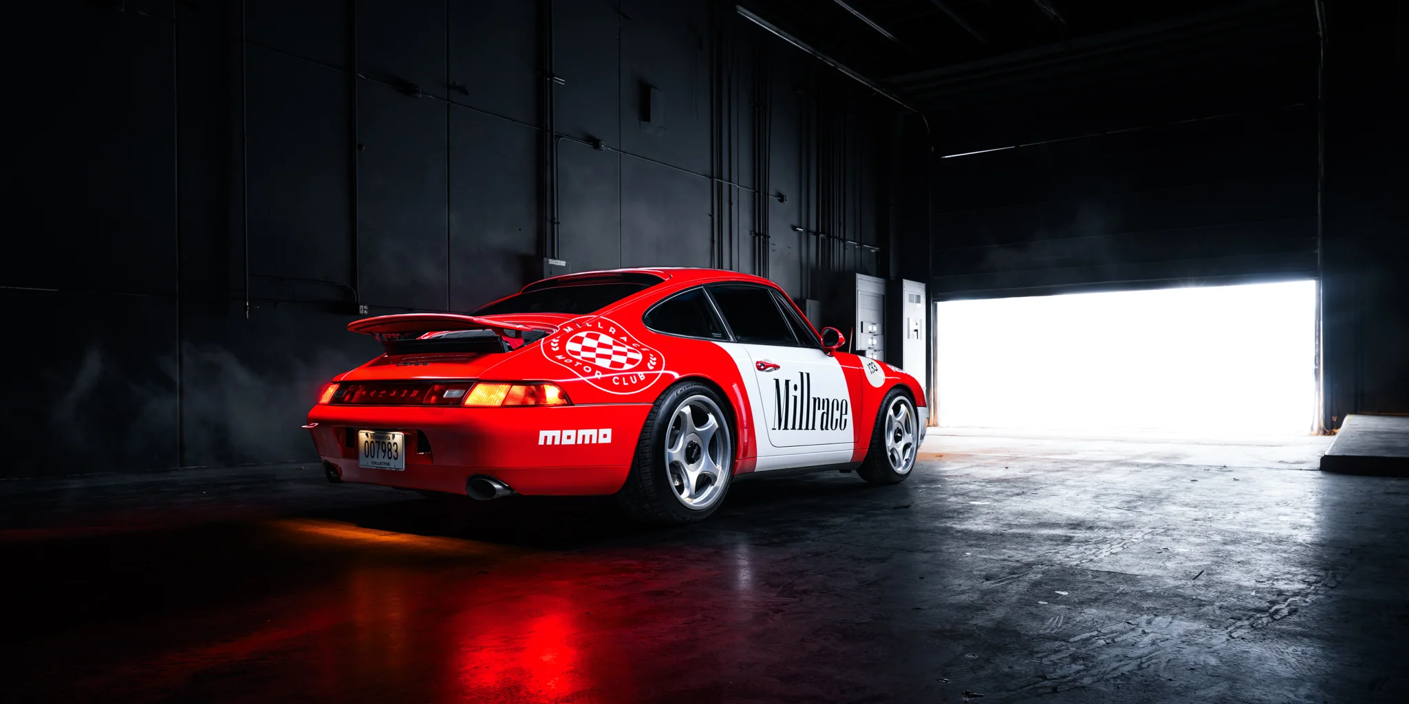 A studio photograph of a Porsche 911 993 in a custom livery in a dark black room