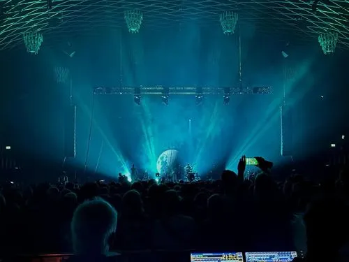 Die Band Bukahara performt in der Halle Münsterland vor einem großen Publikum. In der Mitte ist ein Mond zu sehen und vier Lichtstrahlen gehen an die Decke in der Halle