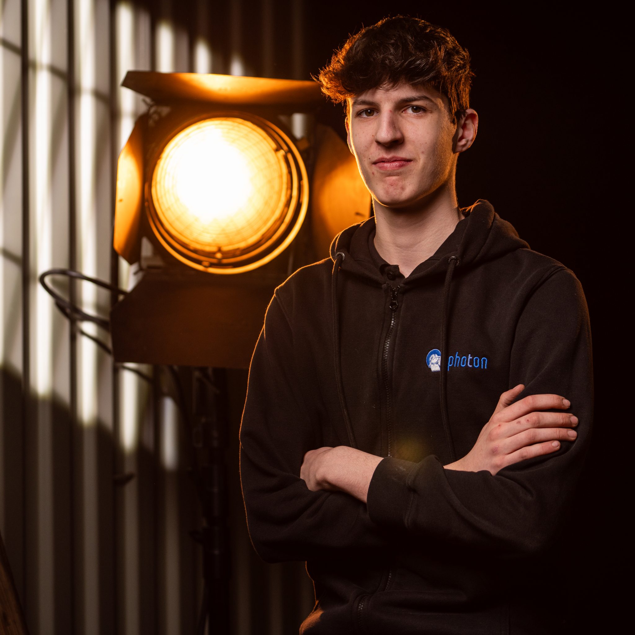 Oliver Odenthal mit Schwarzen Haaren und einem Schwarzen Pullover lächelt in die Kamera, eine Stufenlinse steht hinter ihm