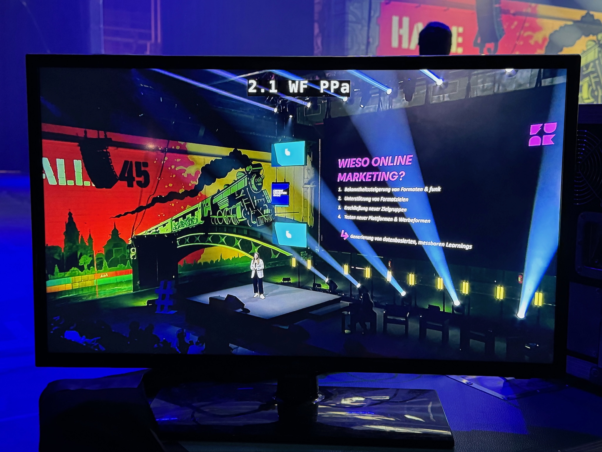 Es wird ein Monitor gezeigt auf dem ein Redner vor einer Led Wand steht und mit unserer Eventtechnik seine Präsentation hält