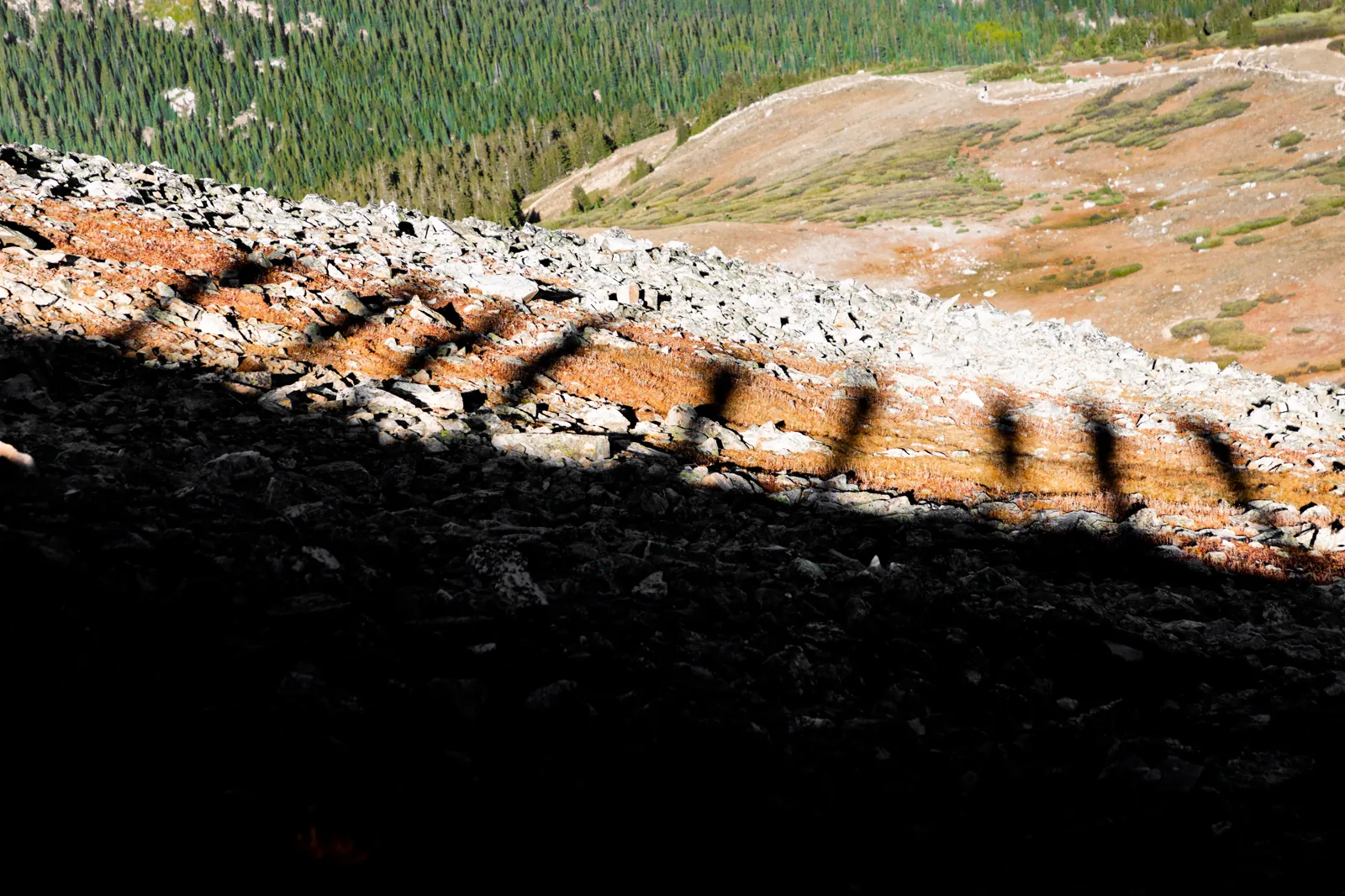 Hiker shadows across a sunlit rock shelf