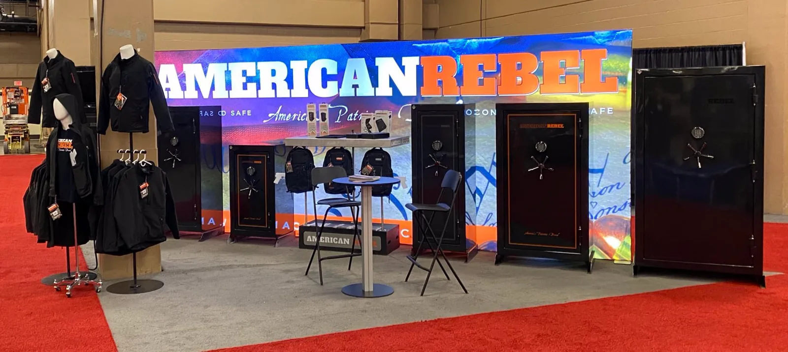 American Rebel trade show booth: show banner backdrop, safes, and concealed-carry apparel