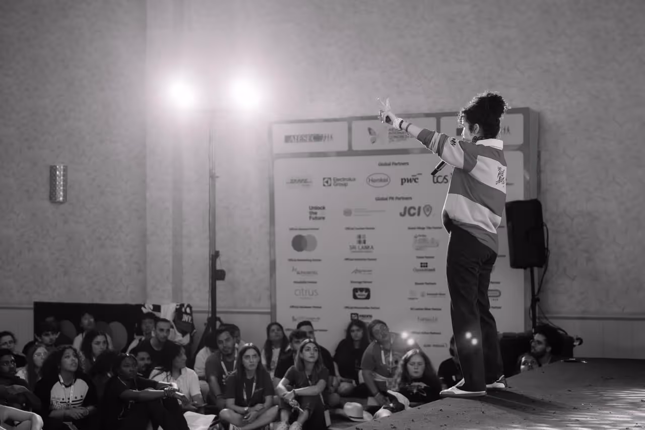 Joven mujer dando una conferencia a otros jóvenes.