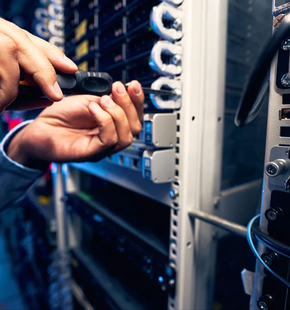 Technician using a screwdriver to adjust hardware components in a server rack.