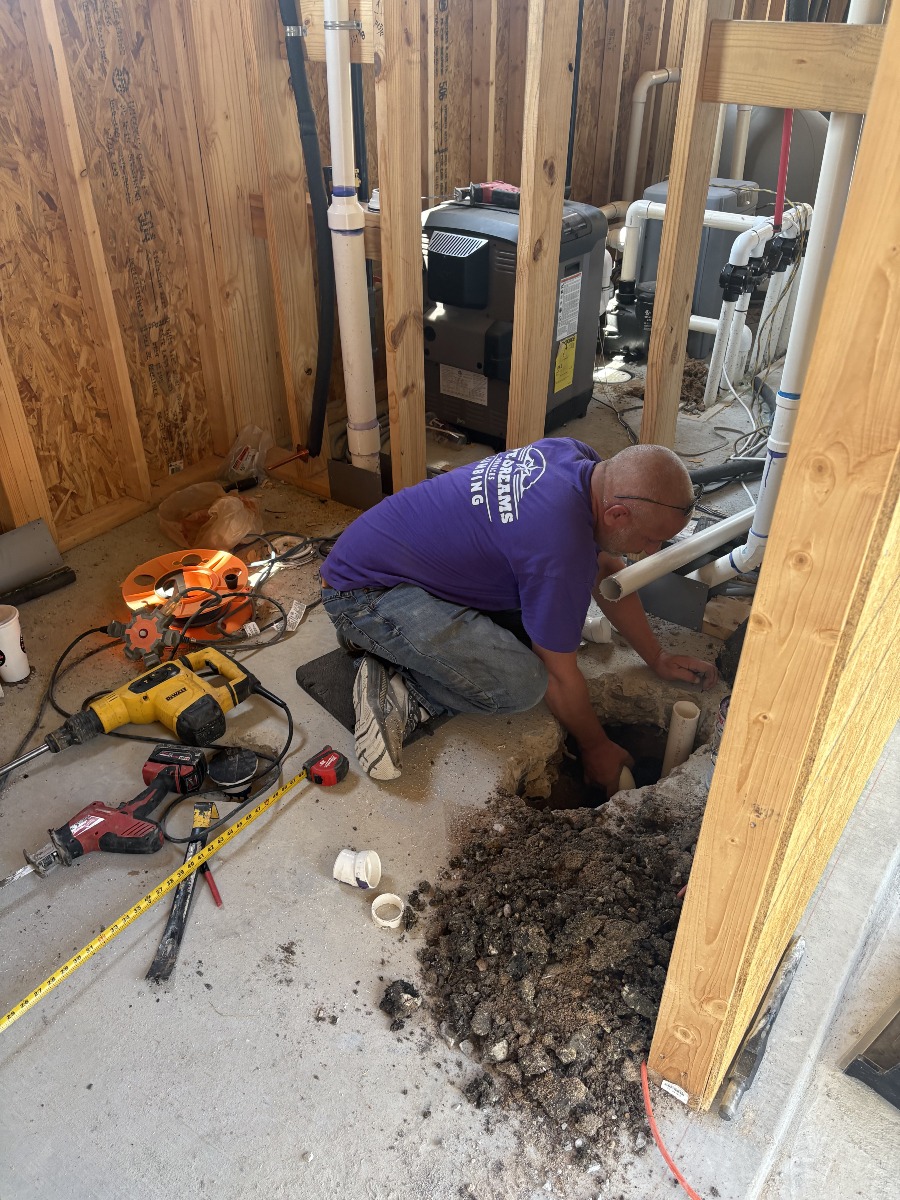 Plumber working on underground piping inside a construction area.