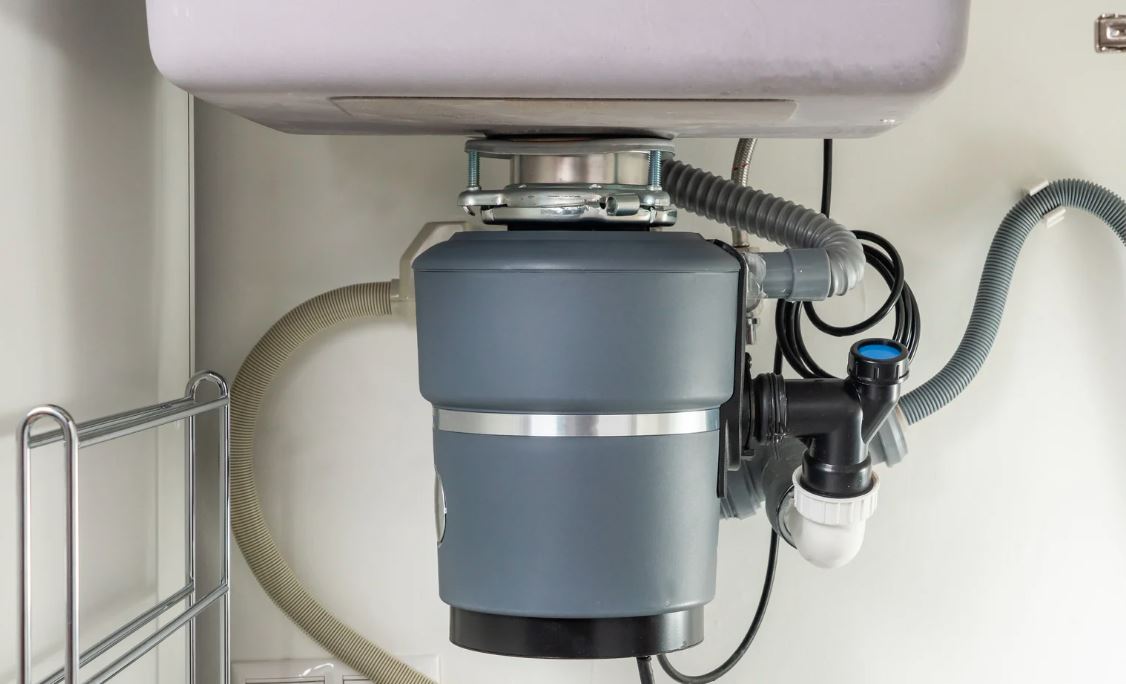 Garbage disposal installed under a kitchen sink.