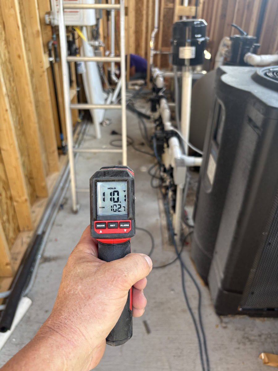 Hand holding an infrared thermometer inside a mechanical room.