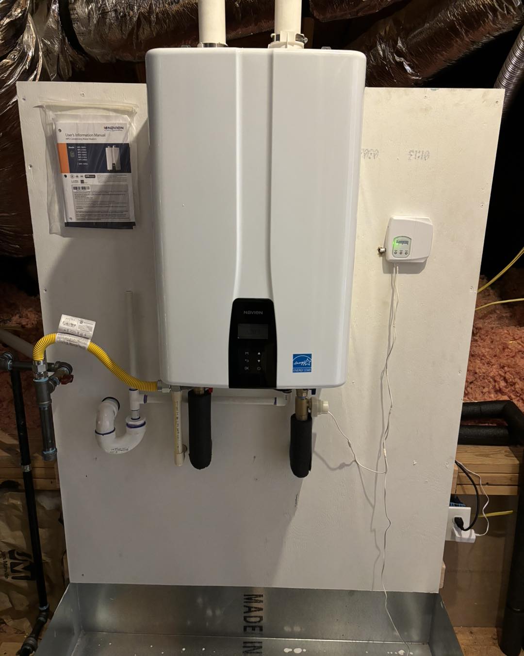 Tankless water heater installed on a wall with connected piping.
