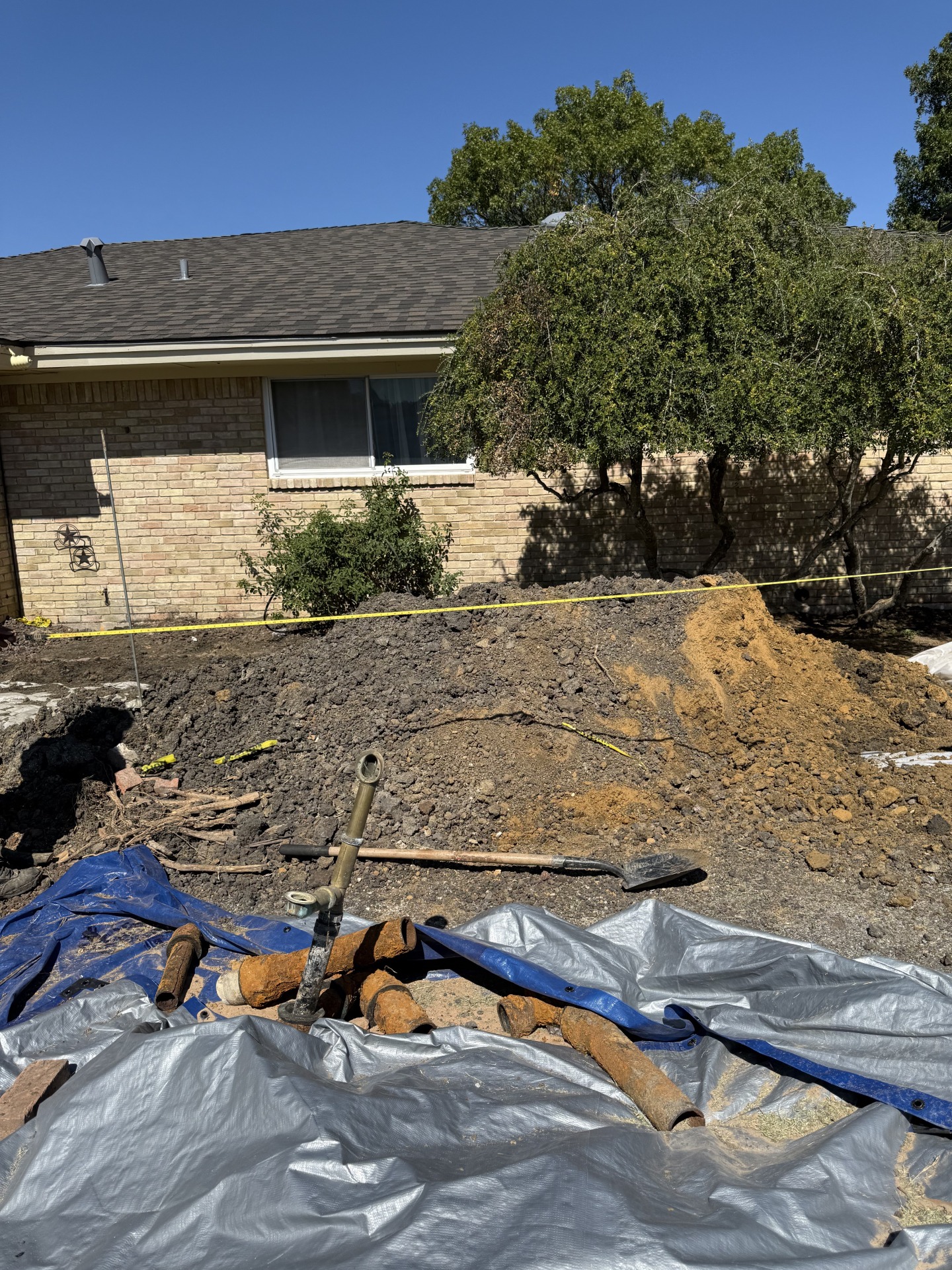 Excavated yard with old rusty cast iron pipes removed.