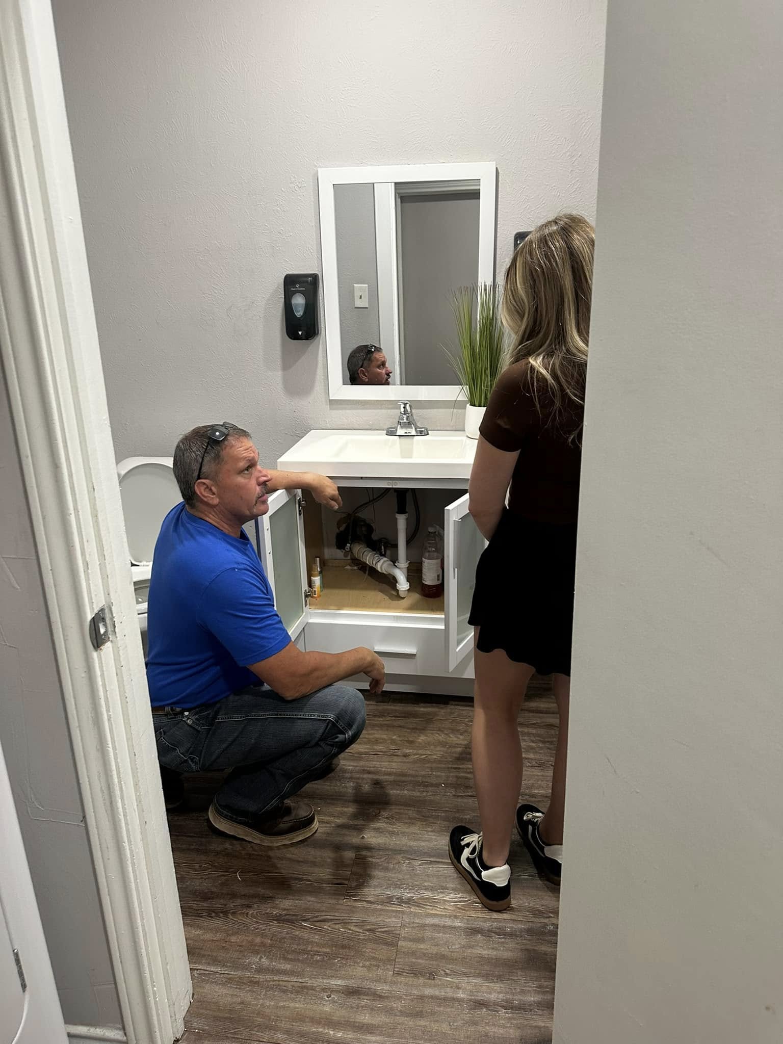 Plumber repairs the plumbing under a sink in Allen, TX.
