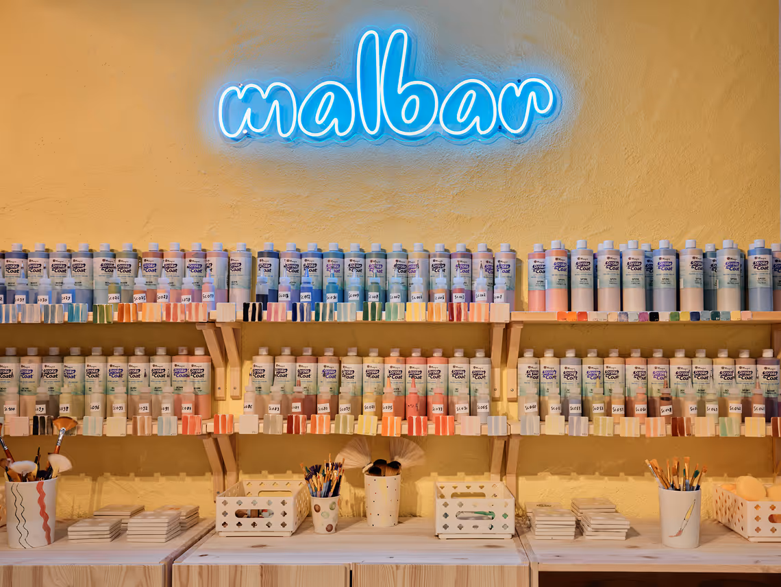 Rundes Keramikgefäß mit grünen, stilisierten Blumenmustern auf cremefarbenem Hintergrund.