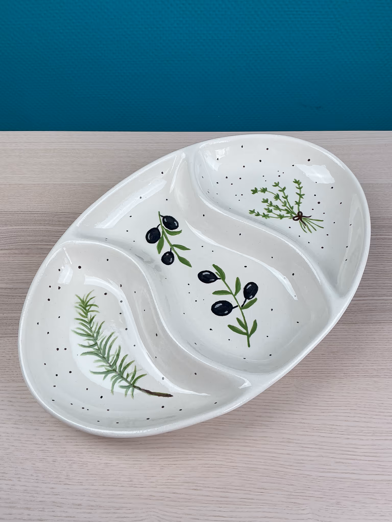 Keramikschale mit drei Fächern und Motiven von Kräutern und Olivenzweigen.