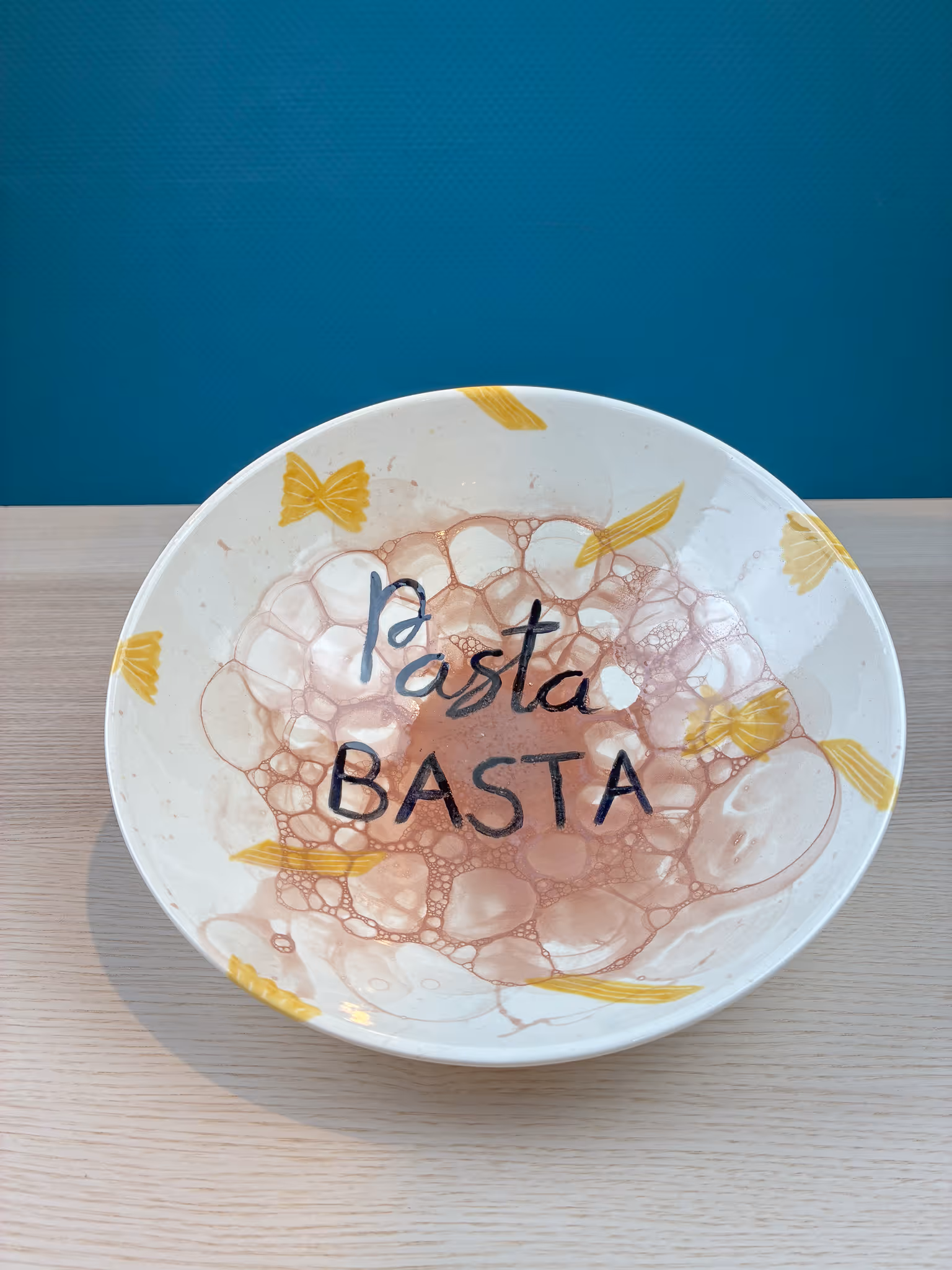 Keramikteller mit gelben Pasta-Motiven bemalt und dem Text Pasta BASTA.