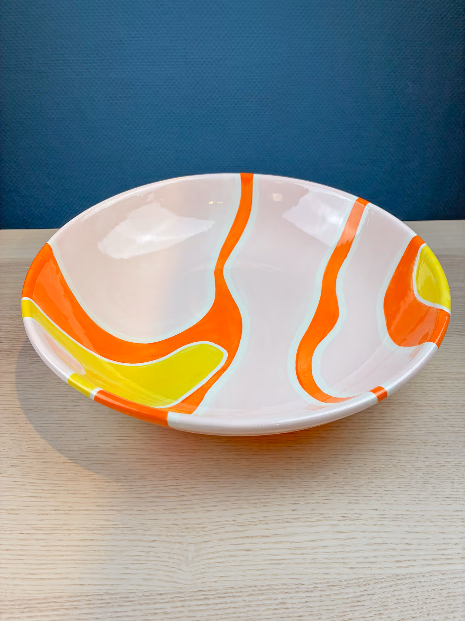Weißer Teller mit abstrakten orange-gelben Mustern.