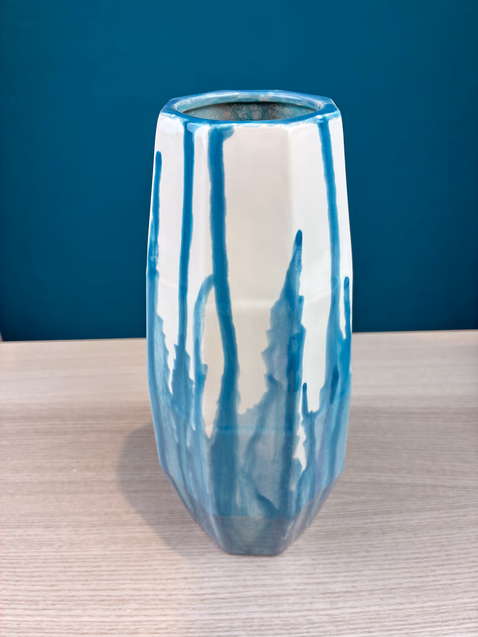 Weiß-blau bemalte Keramikvase auf hellem Holztisch.