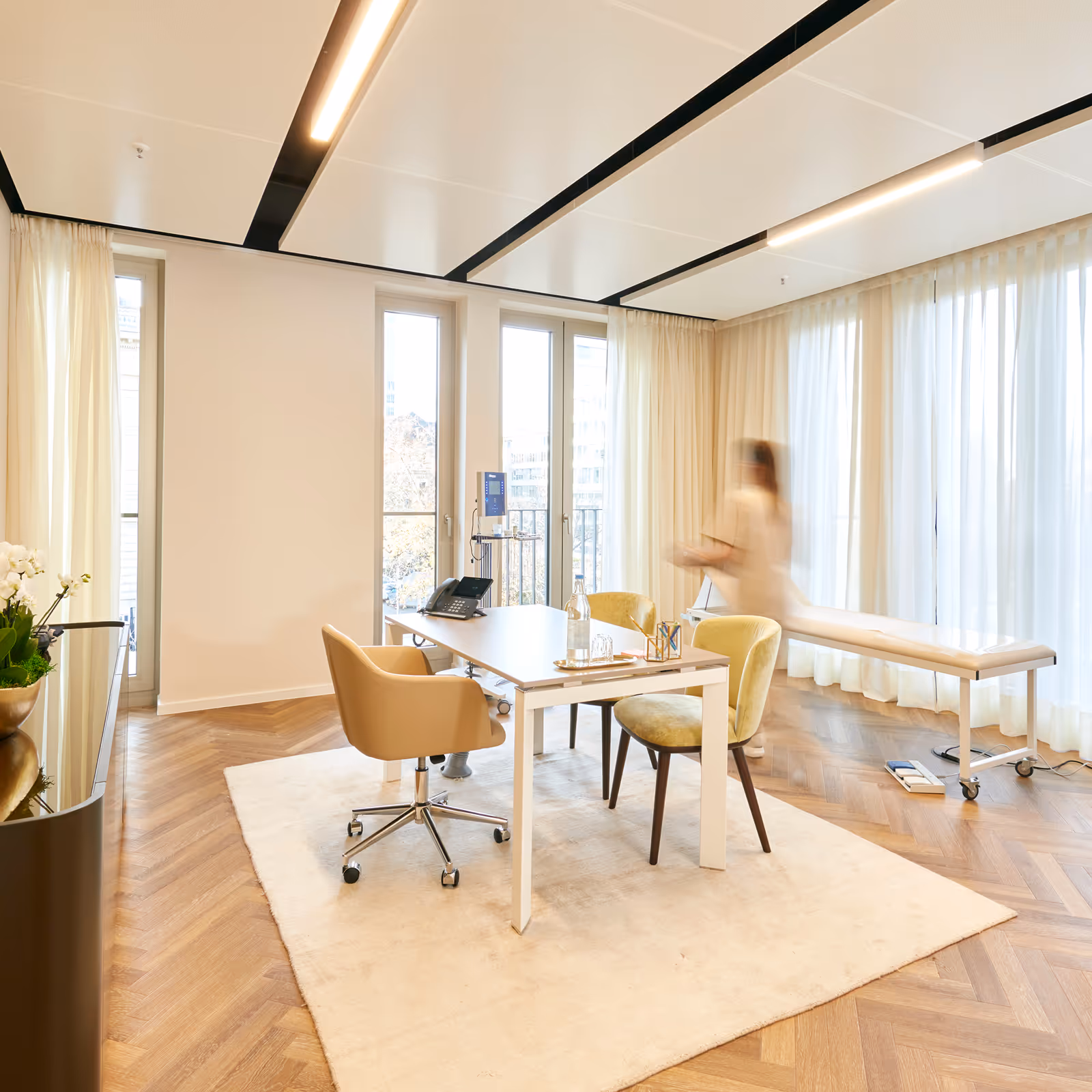 Praxisraum von Magna Med mit einer Mitarbeiterin die durch das Bild läuft