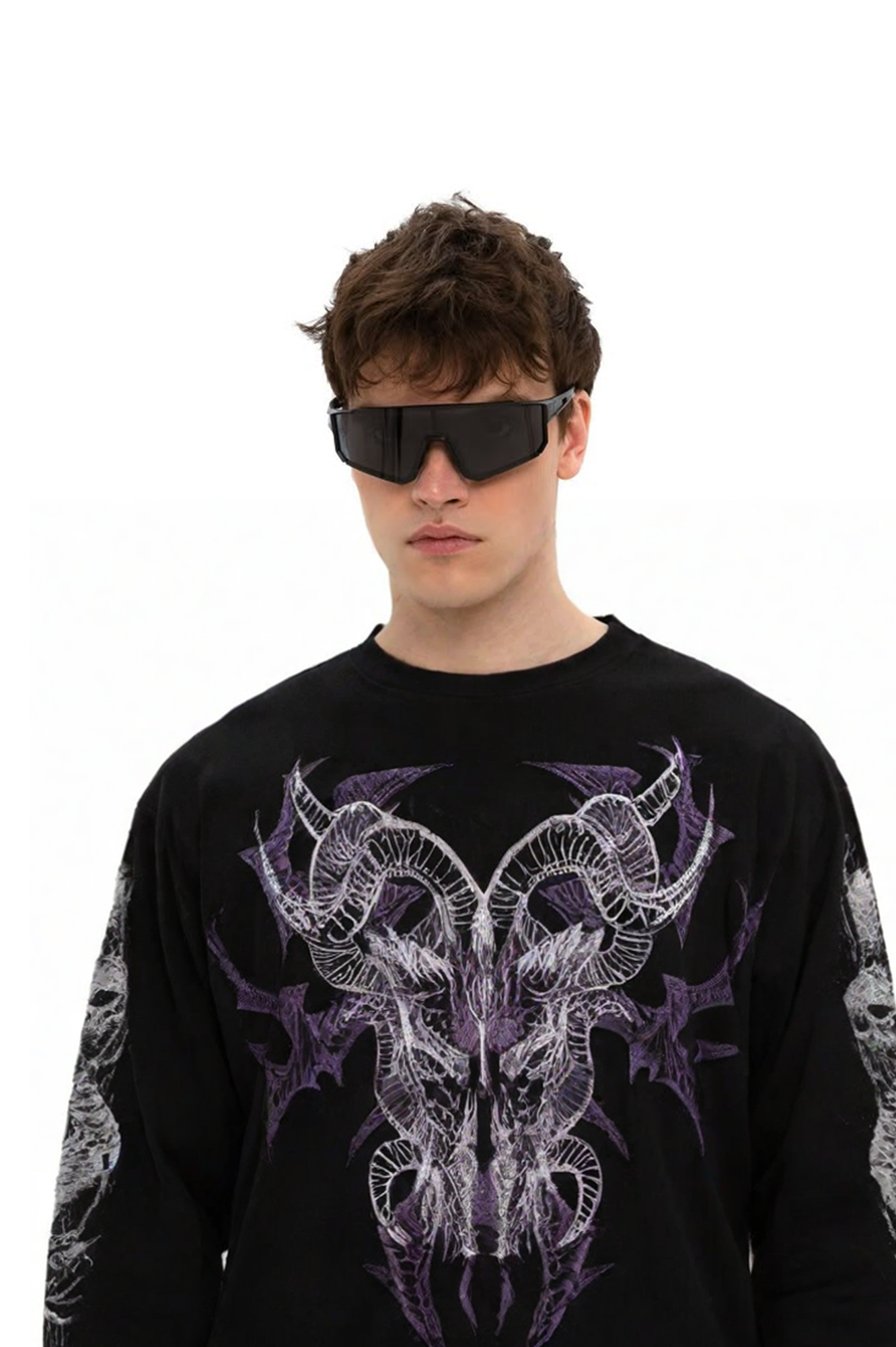 Man wearing futuristic black wraparound sunglasses and a black long-sleeve shirt featuring purple and white ram skull or horned creature design on the front
