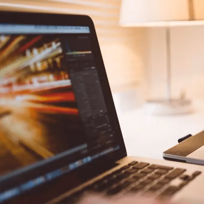 Designer editing photo on laptop with graphics tablet—newsletter inspiration from design industry professionals.