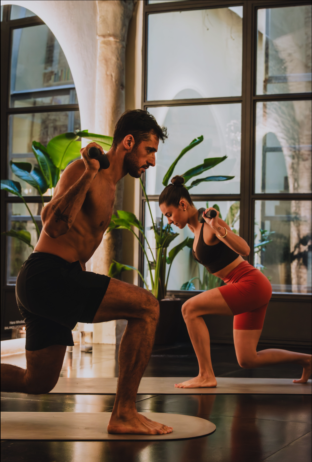 Group of women sitting on exercise mats with medicine balls in a dimly lit yoga or fitness studio.