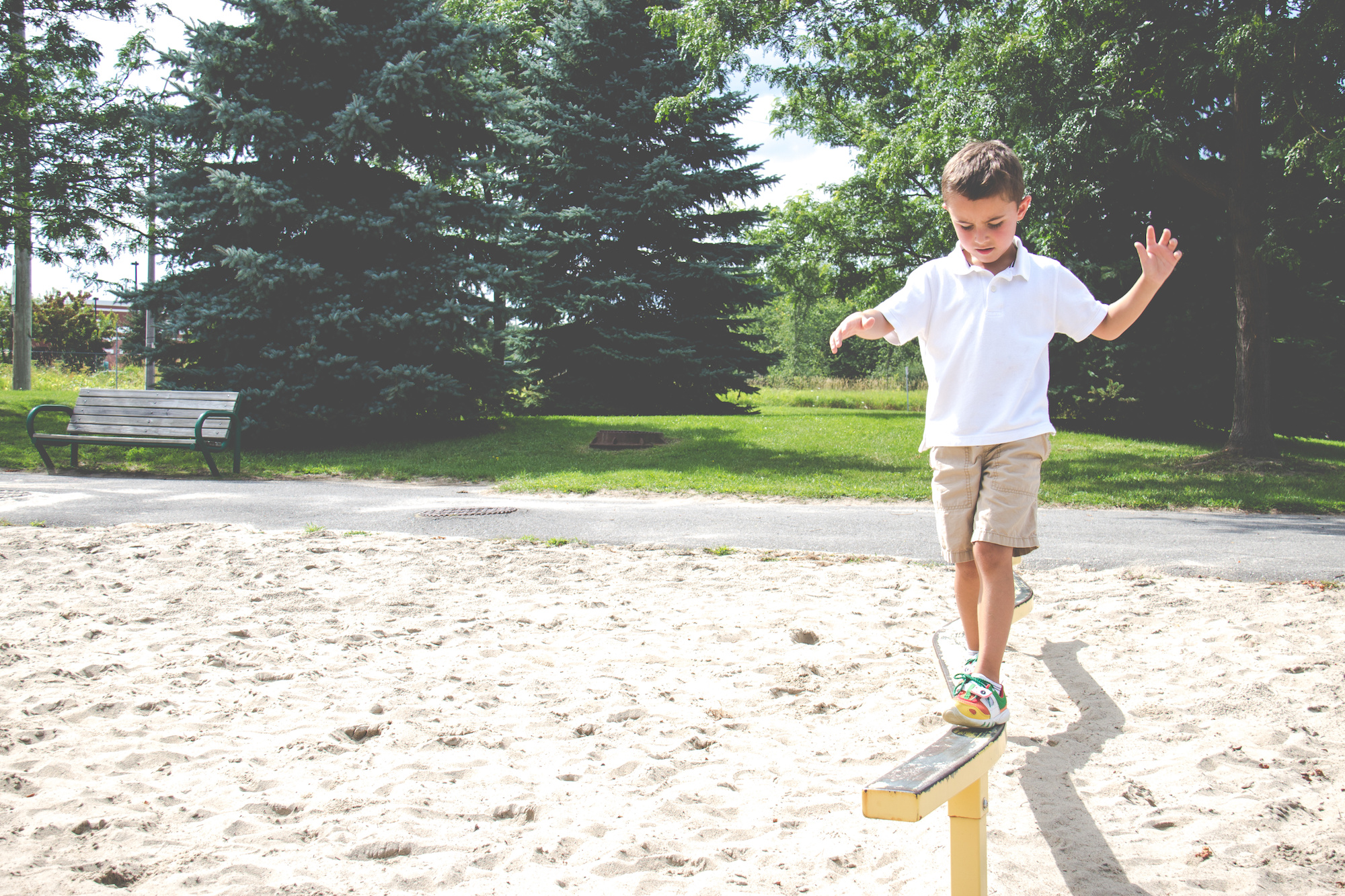A young boy balancing on a beam in a playground