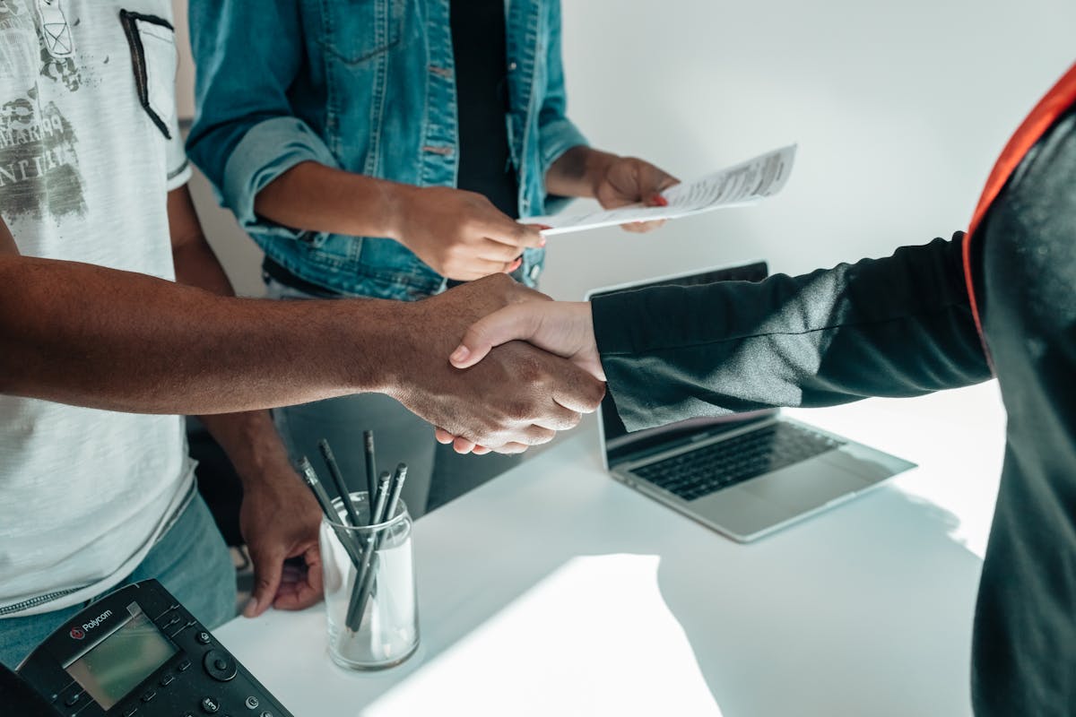 Two professionals shaking hands over documents