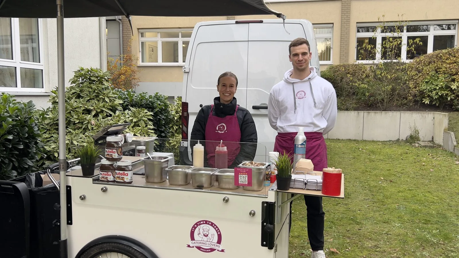 Weißes HappyBike mit zwei Teammitgliedern auf einer Wiese