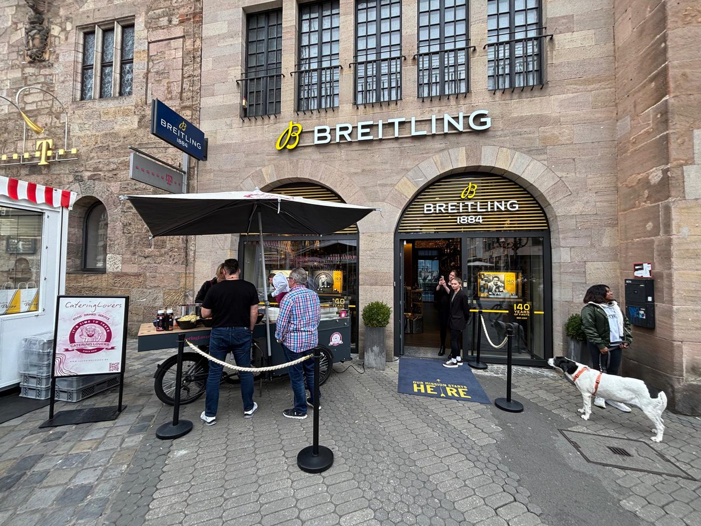 Waffelstand mit Sonnenschirm vor einem Ladengeschäft in der Innenstadt