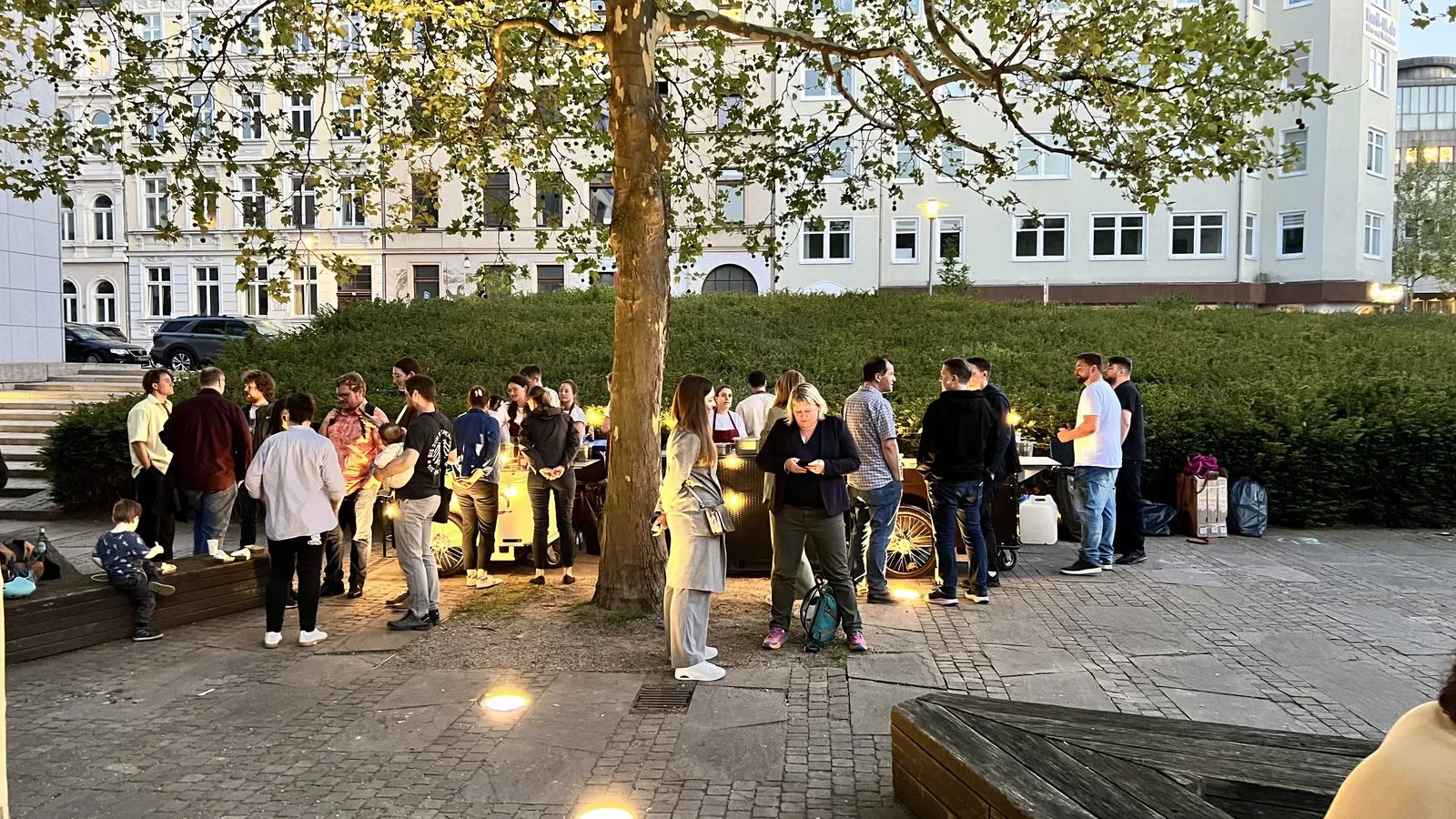 Gäste stehen abends vor dem beleuchteten Waffelstand an