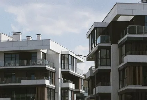 Modern multi-story apartment buildings with balconies under a partly cloudy sky.