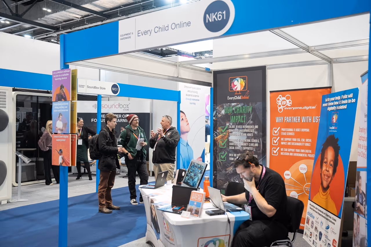 Exhibition booth titled 'Every Child Online' with people conversing and a man working on a laptop surrounded by informational banners.