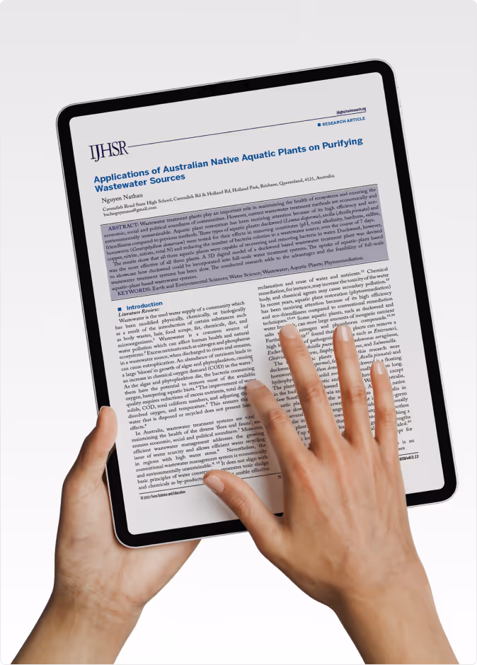 Person holding a tablet displaying a research article titled 'Applications of Australian Native Aquatic Plants on Purifying Wastewater Sources.'