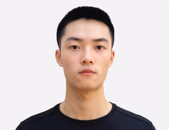 Front-facing portrait of a young man with short black hair wearing a black shirt against a plain white background.