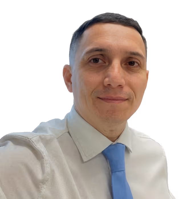 Man with short dark hair wearing a white shirt and light blue tie looking at the camera.