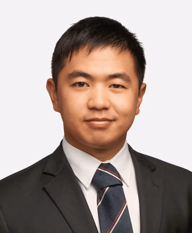 Portrait of a man wearing a black suit, white shirt, and striped tie against a plain background.