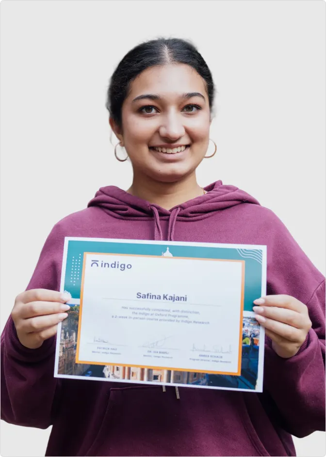 Smiling young woman wearing a purple hoodie holding a certificate from Indigo Research with the name Safina Kajani.