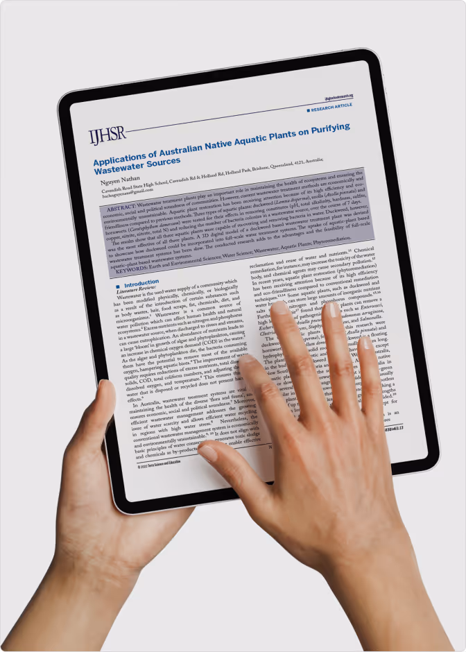 Hands holding and interacting with a tablet displaying a research article titled 'Applications of Australian Native Aquatic Plants on Purifying Wastewater Sources'.