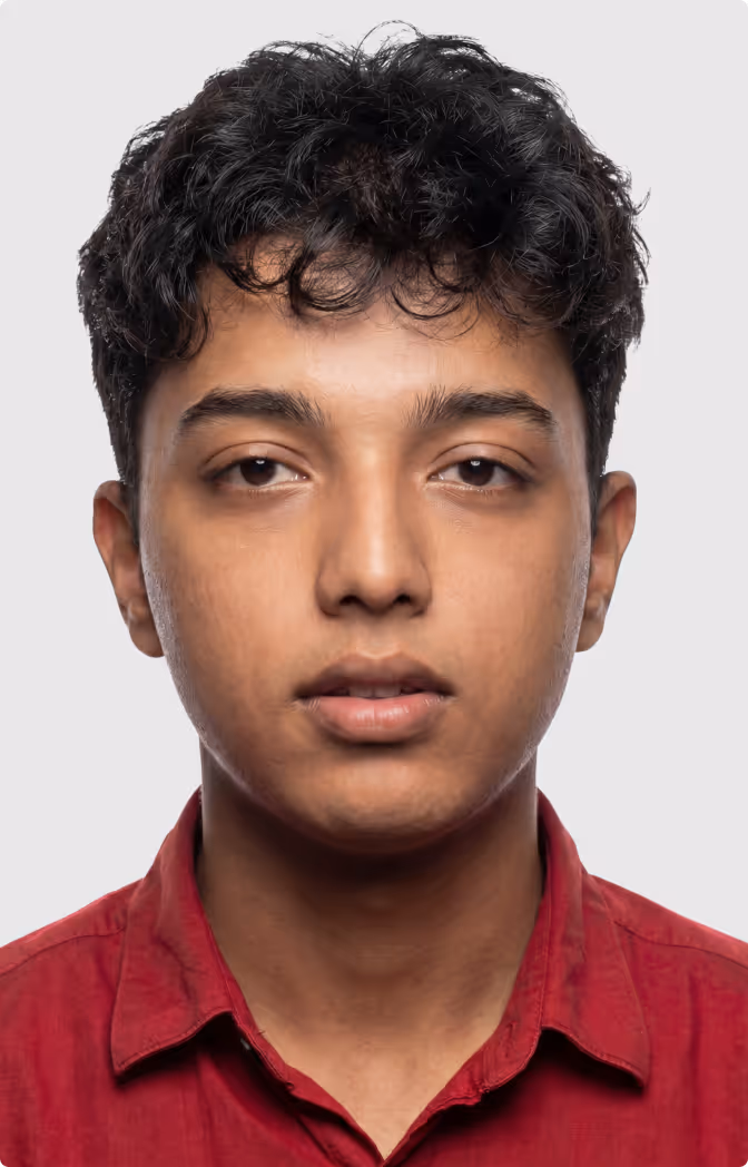 Close-up portrait of a young man with curly black hair wearing a red shirt against a plain background.