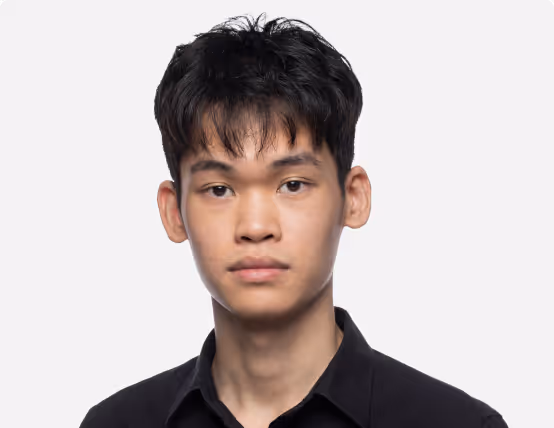 Young man with short black hair wearing a black collared shirt, facing forward with a neutral expression.