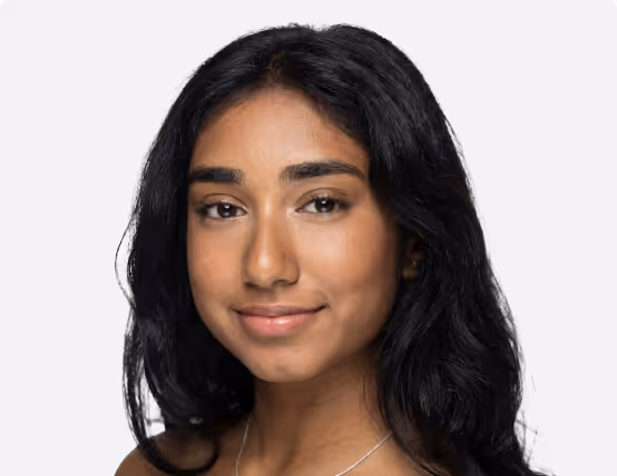 Portrait of a young woman with long black hair smiling against a plain white background.