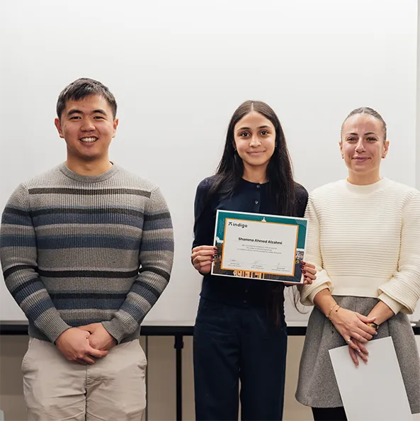 Two scientists in white lab coats discussing in a laboratory with a microscope on the table.
