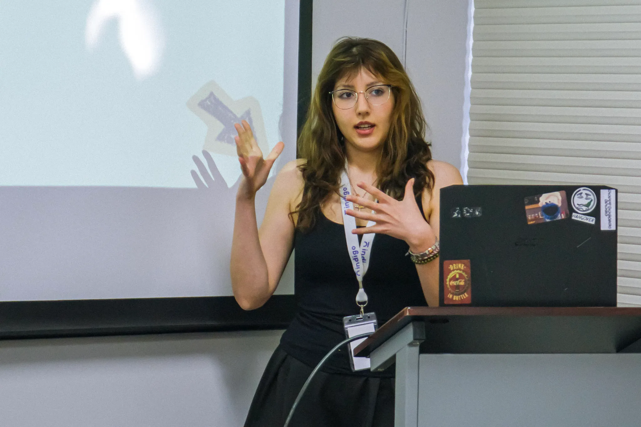 Smiling young woman with long red hair wearing a white t-shirt holding a blue book.