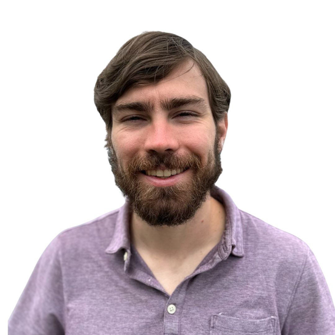 Smiling woman with short brown hair, wearing tortoiseshell glasses and pearl earrings, against a white background.