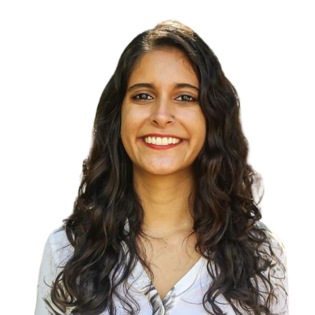Smiling woman with short brown hair, wearing tortoiseshell glasses and pearl earrings, against a white background.