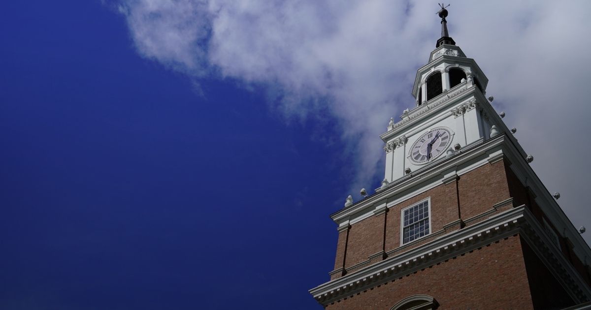 Person sitting alone in an auditorium reading sheet music among rows of empty beige and brown seats.