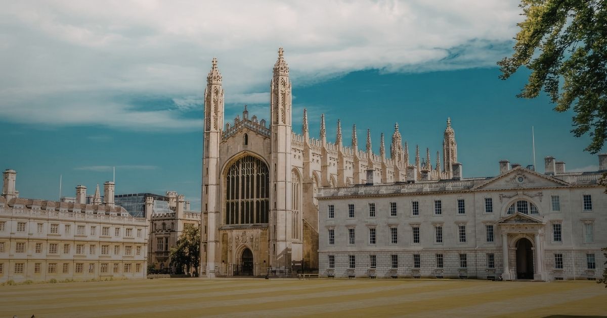 Person sitting alone in an auditorium reading sheet music among rows of empty beige and brown seats.