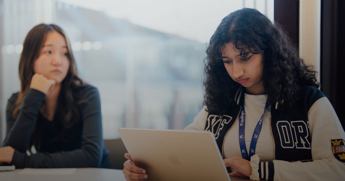 Person sitting alone in an auditorium reading sheet music among rows of empty beige and brown seats.