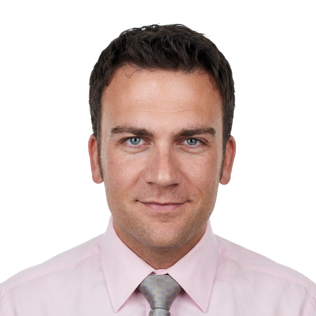 Woman with long brown hair and blue eyes smiling, wearing a black jacket over a white top.